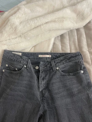 Levi's grå jeans straight fit - Klassiska grå Levi's jeans med rak passform. Jeansen har knappgylf, bälteshällor och den ikoniska läderlappen bak i midjan. Tillverkade i slitstark bomullsdenim och har en tidlös look som funkar till allt. Nästan aldrig använd! Storlek 28