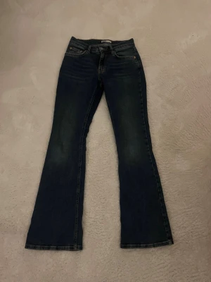 Mörkblå bootcut jeans från Gina tricot  - Snygga mörkblå bootcut jeans med klassisk femficksdesign och normal passform. Jeansen har utsvängda ben och är tillverkade i ett mjukt bomullsmaterial med lite stretch för extra komfort. Perfekta för en trendig och avslappnad look.