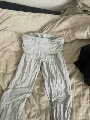 Grå yogapants från Gina Tricot - Säljer ett par ljusgrå leggings från Gina Tricot i mjukt bomullsmaterial. Sitter tight hela vägen ner. Perfekta för en chill och bekväm stil. Dom är lite slitna längst ner men det är inget man tänker på. Storlek S.