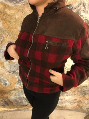 Rutig jacka med bruna detaljer - Snygg jacka med röd- och brunrutigt mönster och bruna partier upptill och på ryggen. Jackan har dragkedja framtill, bröstficka med dragkedja och hög krage. Perfekt för dig som vill sticka ut med en unik stil.