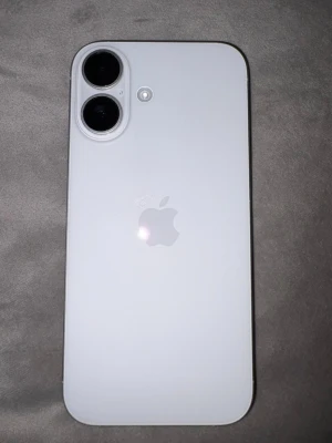 Vit iPhone med dubbla kameror - Snygg vit iPhone 16 med stilren design och två stora kameralinser på baksidan. Telefonen har en platt framsida med en modern skärm och Apples logga i mitten på baksidan. Batteri 100% inga skador eller defekter 