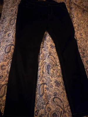 Svarta raka jeans med kontrastsöm - Snygga svarta jeans med raka ben och kontrastsömmar. Klassisk femficksmodell i jeansmaterial som passar perfekt till en avslappnad stil. Jeansen har en enkel design utan extra detaljer och är lätta att matcha med olika outfits.