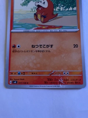Pokémonkort Yawnmakuhita SV8 017/106 - Japanskt Pokémonkort med Yawnmakuhita från Scarlet & Violet-serien. Kortet har en orange bakgrund och visar en tecknad Pokémon vid vattnet. Kortnummer SV8 017/106. Perfekt för samlare av japanska Pokémonkort.