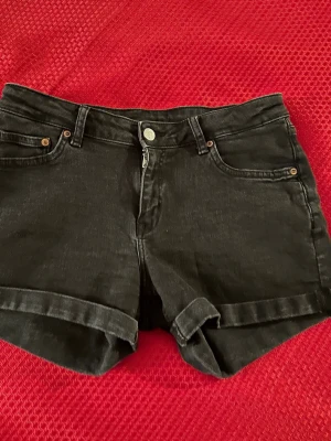 Svarta jeansshorts från Denim Co. - Svarta jeansshorts från Denim Co. med klassisk femficksmodell och uppvikta benslut. Stängs med dragkedja och knapp. Perfekta för sommaren och enkla att matcha med olika toppar.