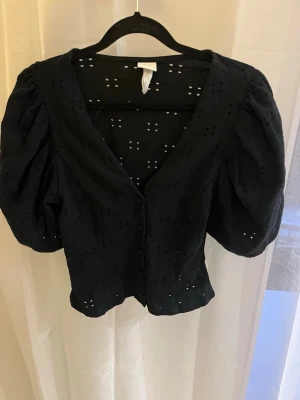 Svart blus med puffärm och broderi - Svart blus med puffiga korta ärmar och v-ringning 