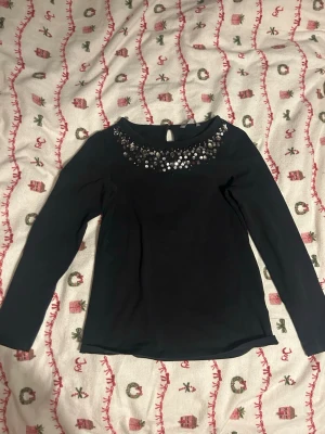 Svart topp med paljetter - Snygg svart långärmad topp med glittriga paljetter. Storlek 146-152 men den passar mig som har storlek xs/s, men har lite korta ärmar.