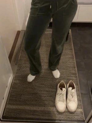 Gröna mjukisbyxor i velour - Mysiga gröna mjukisbyxor i velour med raka ben och resår i midjan. Byxorna har snörning och två fickor framtill. Perfekta för chill eller när du vill vara bekväm men ändå se snygg ut.