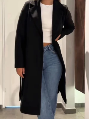 Svart lång kappa  - Stilren svart kappa i lång modell med klassisk krage och raka ärmar. Perfekt för dig som gillar en tidlös look. Kappan har en rak passform och är enkel att matcha till olika outfits. Från Vero moda, storlek XS använd 2 gånger