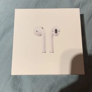 Apple AirPods med laddningsetui - Säljer ett par vita Apple AirPods med laddningsetui. Trådlösa in-ear-hörlurar med stilren design och smidig anslutning till iPhone och andra Apple-enheter. Perfekta för musik, samtal och vardagsbruk. Köpe de på Apple på emporia för full pris.