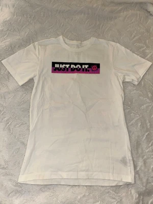Nike Just Do It vit t-shirt (S) - Säljer en vit t-shirt från Nike med färgglada 'Just Do It.'-tryck i svart, rosa och lila på både fram- och baksidan. T-shirten har korta ärmar och är gjord i mjuk bomull. Använd två gånger.            Kille storlek!!!  Skriv vid frågor 🥰