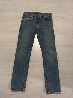 Nudie Jeans - Klassiska nudie jeans i blå denim med raka ben och normal passform. Perfekta för en avslappnad och tidlös stil. Lite slitet i fickan men inget som syns när man har dom på. Skriv för bild på.