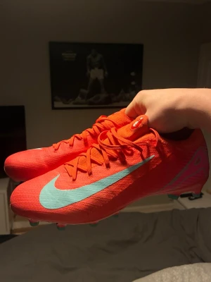 Nike Mercurial röda fotbollsskor - Säljer ett par Nike Mercurial fotbollsskor i en riktigt snygg röd färg med turkosa detaljer och snörning har endast använts 2 gånger men tyckte dem vara alldeles för färgiga för mig men en trevlig sko men jättebra passform. Box följer med