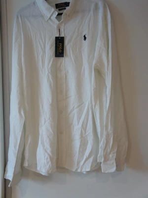 Vit overshirt skjorta från Polo Ralph Lauren - Klassisk vit skjorta från Polo Ralph Lauren med broderad logga på bröstet. Skjortan har knappar framtill, krage och långa ärmar. Tillverkad i mjuk bomull för en bekväm känsla och stilren look. ❗️OBS❗️ - Det är en overshirt, skriv till mig innan köp! 🙌🏼