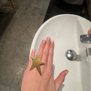 Stor stjärnring i guld - Cool ring med en stor stjärna i guldigt metallmaterial. Statement-accessoar som verkligen drar blickarna till sig och passar perfekt för dig som vill sticka ut. Ringen har en unik och trendig design.