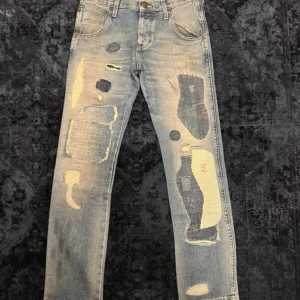 Patchwork Wrangler jeans - Säljer ett par sjukt feta patchwork wrangler jeans. Längden är 32. Tveka inte att höra av er vid frågor!