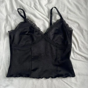 Svart topp med spets  - Svart spetstopp i lite styvare material. 