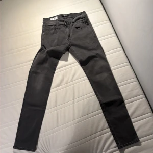 Mörkgrå Replay jeans skinny fit - Snygga mörkgrå jeans från Replay med klassisk femficksdesign och skinny passform. Jeansen har raka bakfickor med diskreta sömmar och svart Replay-läderpatch i midjan. Perfekta för dig som gillar en smal siluett och stilren look.