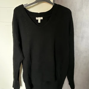 Svart stickad v-ringad tröja H&M - Svart stickad tröja från H&M med v-ringad hals och långa ärmar. Enkel och stilren design som passar perfekt till jeans eller kjol. Mjuk och skön känsla, perfekt för kyliga dagar. Snygg att bära lager på lager.
