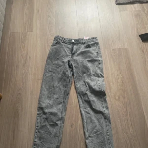 Grå jeansbyxor från LMTD S/M - Snygga grå jeansbyxor från LMTD i storlek S/M. Byxorna har klassisk femficksdesign, knapp och dragkedja framtill samt raka ben. Materialet är slitstarkt denim och färgen är tvättad grå med coola detaljer i sömmarna.