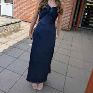 Marinblå balklänning med smala axelband - Elegant marinblå långklänning med smala axelband och figurnära passform. Klänningen har en enkel, stilren design och är tillverkad i ett glansigt material som ger en lyxig känsla. Perfekt för dig som vill ha en klassisk och tidlös look. Jag är även ganska lång så klänningen kan se kort ut på mig då jag även hade klackar. Jag är 170❤️