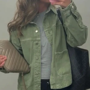 Grön jeansjacka Zara - Snygg grön jeansjacka med stora framfickor och knappar framtill. Jackan har en avslappnad passform och klassisk krage, perfekt att slänga på sig över en t-shirt. Enkel och stilren design som funkar till det mesta. 