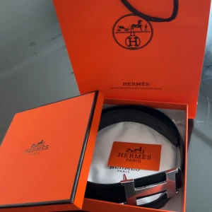 Svart Hermès skärp med H-spänne - Säljer ett svart skärp från Hermès med ikoniskt H-spänne i silverfärgad metall. Bältet är gjort i exklusivt skinn och levereras i originalförpackning med dustbag och certifikat. Perfekt accessoar för att lyfta din outfit.