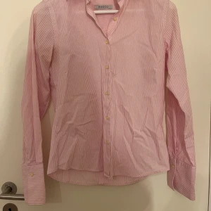 Rosa och vit Rocco skjorta - - Rocco                                                                              - Mycket bra skick                                                         - Storlek 36/S                                                                  Väldigt fin Rocco skjorta som är både rosa och vit med ränder och passar både till vardags och formellt. Svarar gärna på frågor och kan försöka fixa bättre bilder om det behövs💕