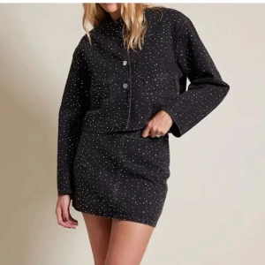 Set - svart/mörkgrå jeans jacka och matchande kjol - Snygg svart/mörkgrå jeans jacka med matchande jeanskjol med diamanter på. Kjolen har en rak passform och dragkedja bak. 