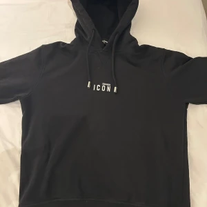 Svart Dsquared2 Hoodie - Svart hoodie från Dsquared2 med vit 'ICON'-text på bröstet. Klassisk huva med snörning och metalländar, samt långärmad design ( köpt på miinto för 1500:- ) 