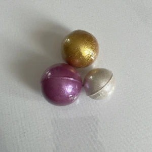Glittriga badbomber i kulform - Tre badbomber i rund kulform med metallicfinish. Färgerna är guld, rosa och pärlemovit.