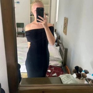 Svart offshoulder klänning - Svart axelbandslös klänning från NAKD med offshoulder-design och figurnära passform. Klänningen är ribbad och har en medellång längd. Aldrig använd 