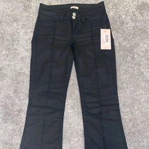 Svarta coated jeans från Nelly - Super snygga svarta skinnbyxor från Nelly med låg midja och bootcut. Snygga markerade sömmar och broderade bakfickor. 😍 Dom är helt nya och endast testade! Säljer för dom va för små för mig ☺️Skriv vid frågor och skriv gärna innan ni köper❤️❤️