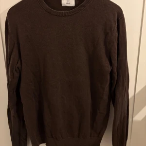 Mörkbrun stickad tröja från Bläck - En stilren mörkbrun stickad tröja från Bläck i storlek M. Tröjan har rund halsringning och långa ärmar, perfekt för lager-på-lager under kyligare dagar. Enkel och klassisk design som funkar till många olika outfits.