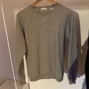 Grå sweatshirt från Pier One - En stilren grå sweatshirt från Pier One med rund halsringning och långa ärmar. Tröjan har en klassisk passform och är tillverkad i mjuk bomullsmix, perfekt för lager-på-lager under kyliga dagar.