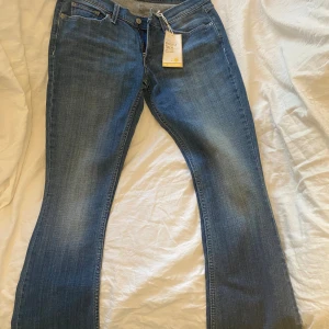 Levi's 524 Skinny Flare jeans blå - Snygga Levi's 524 Skinny Flare jeans i klassisk blå denim. Modellen har låg midja och smal passform upptill som övergår i utsvängda ben. Stretchigt material för extra komfort och coola detaljer som dekorativ bakficka och Levi's etikett. Perfekta för en trendig look.