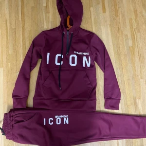 Vinröd hoodie DSQUARED2 Ibrahimovic - Säljer en vinröd hoodie från DSQUARED2 x Ibrahimovic med stor 'ICON' print på framsidan och en grafisk bild samt logga på ryggen. Hoodien har huva med snörning och är tillverkad i mjukt material, perfekt för chill eller streetwear.