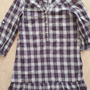 Skjortklänning - Rutig skjortklänning från H&M i storlek 34. Klänningen har en klassisk krage, knappar framtill och trekvartsärmar med knappdetalj. Färgerna är marinblå, vit och röd, och materialet är mjuk bomull. Perfekt för en chill och avslappnad stil.
