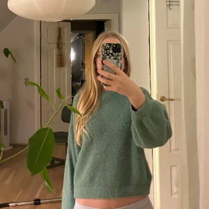 Grön fluffig tröja från Lindex - Mysig turkos/grön tröja från Lindex med fluffig yta och avslappnad passform. Tröjan har långa ärmar och en enkel rund halsringning, perfekt för dig som gillar en chill och comfy stil. Passar dig som vill ha en basic men ändå trendig look.