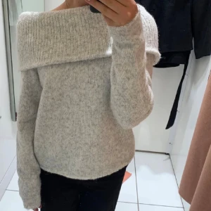 Grå offshoulder stickad tröja - Supermysig grå stickad tröja med bred offshoulder-krage och långärmad modell. Perfekt för kyliga dagar och ger en chill men ändå snygg vibe. Mjuk och skön känsla tack vare det stickade materialet.