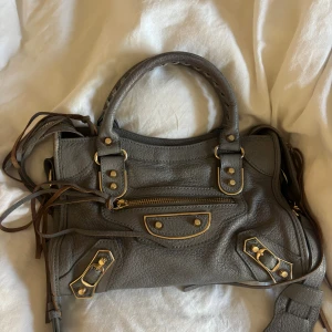 Balenciaga väska  - I modellen mini city bag. Finns kvitto som medföljer. Sliten på vissa ställen men ger endast karaktär till väskan. Kan skickas bild på de med om intresse finns. Såå cool och jättefin väska i ett bra skick för sin ålder.
