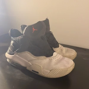 Nike Jordan 1 svartvita sneakers - Svartvita Nike Jordan 1 sneakers med högt skaft och röd Jumpman-logga på plösen. Snygg kontrast mellan svart textil och vitt skinn, samt robust sula med tydligt mönster och Jumpman under. Flight-detalj bak i rött. Perfekt för dig som gillar basketstil.