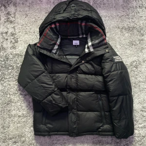 Burberry vinterjacka - Riktigt fet och praktisk vinterjacka som även kan bäras som väst tack vare de löstagbara ärmarna. En väldigt stilren jacka i storlek M som passar perfekt till kalla vinterdagar där något tjockare plagg kan behövas❄️. Invändigt är jackan utrustad med mjukt foder i krage och luva med det klassiska rutiga mönstret för en lyxig touch. Detta ger en väldigt behaglig upplevelse i praktiken och självklart även elegans på samma gång⚜️. Hör gärna av dig vid minsta fundering om t.ex, mått, pris elr så!