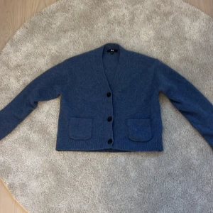 Blå kofta från Uniqlo  - Mysig blå kofta från Uniqlo i storlek XS. Koftan har v-ringning, tre knappar framtill och två praktiska fickor. Köptes för 400. Mycket bra skick.