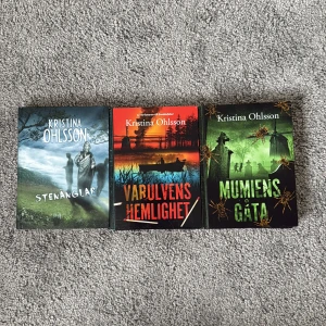 Stenänglar, Varulvens hemlighet, Mumiens gåta - Tre spännande böcker av Kristina Ohlsson med mystiska och övernaturliga teman. Perfekt för dig som gillar äventyr, gåtor och lite ryslig stämning! Omslagen lockar med statyer, varulvar och mumier – en riktig bladvändartrio för unga läsare. Säljer alla dessa böcker för 250 kr, perfekt för yngre läsintresserade. 