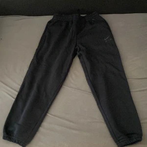 Svarta Nike Air mjukisbyxor L - Svarta mjukisbyxor från Nike Air med elastisk midja och muddar vid benslut. Byxorna har diskret Nike Air-logga i silver på ena benet och är tillverkade i mjukt material som passar perfekt för chill eller träning.