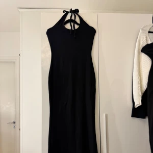 Svart långklänning - Svart långklänning med knytning i nacken. Klänningen har en stilren, figurnära passform. 
