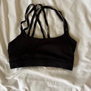 Svart linnetopp med korsade band från HM - Säljer en svart linnetopp med smala korsade axelband både fram och bak. Toppen har en enkel, stilren design och är tillverkad i ett stretchigt material som passar perfekt till träning eller som ett snyggt basplagg. Snygg och bekväm med sportig känsla.