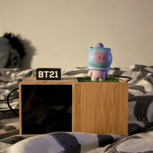 BT21 Mang Digital Väckarklocka - Snygg digital väckarklocka med BT21 Mang-figur. Klockan har en modern design i trä och svart, med konstgräs och USB-anslutning. Fungerar som alarmklocka och dekoration. Gott skick, mindre ytslitage kan förekomma. Perfekt för fans av BT21 och K-pop. Nypris: 500kr