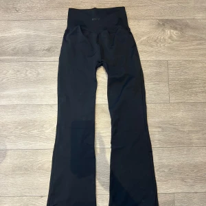 Aimn Black Shape Seamless Flare Tights - Yogapants från Aimn i deras stretchiga Shape Seamless-material med booty-contouring effekt som framhäver ens former. Hög ribbad midja och utsvängda ben. Endast testade och tvättade 1 gång, supersköna men tyvärr för små för mig.   Storlek: S Färg: svart  Material: 92% polyamid, 6% elastan. Nypris: 799 kr
