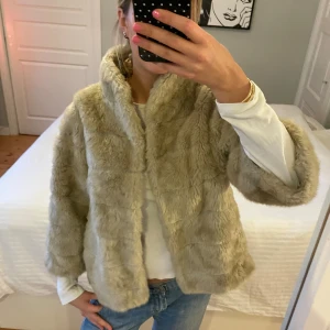 Beige pälsjacka med krage - Säljer en supermjuk och fluffig beige pälsjacka med hög krage. Jackan har en avslappnad passform och långa ärmar, perfekt för att hålla sig varm och snygg under kyliga dagar. Enkel att styla till både jeans och klänning.